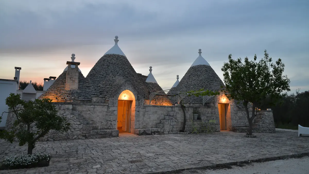 I trulli di Trullux al crepuscolo, con le porte illuminate