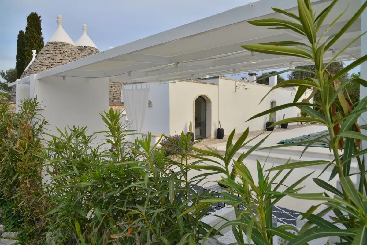 La pergola bianca e i coni dei trulli fra gli oleandri