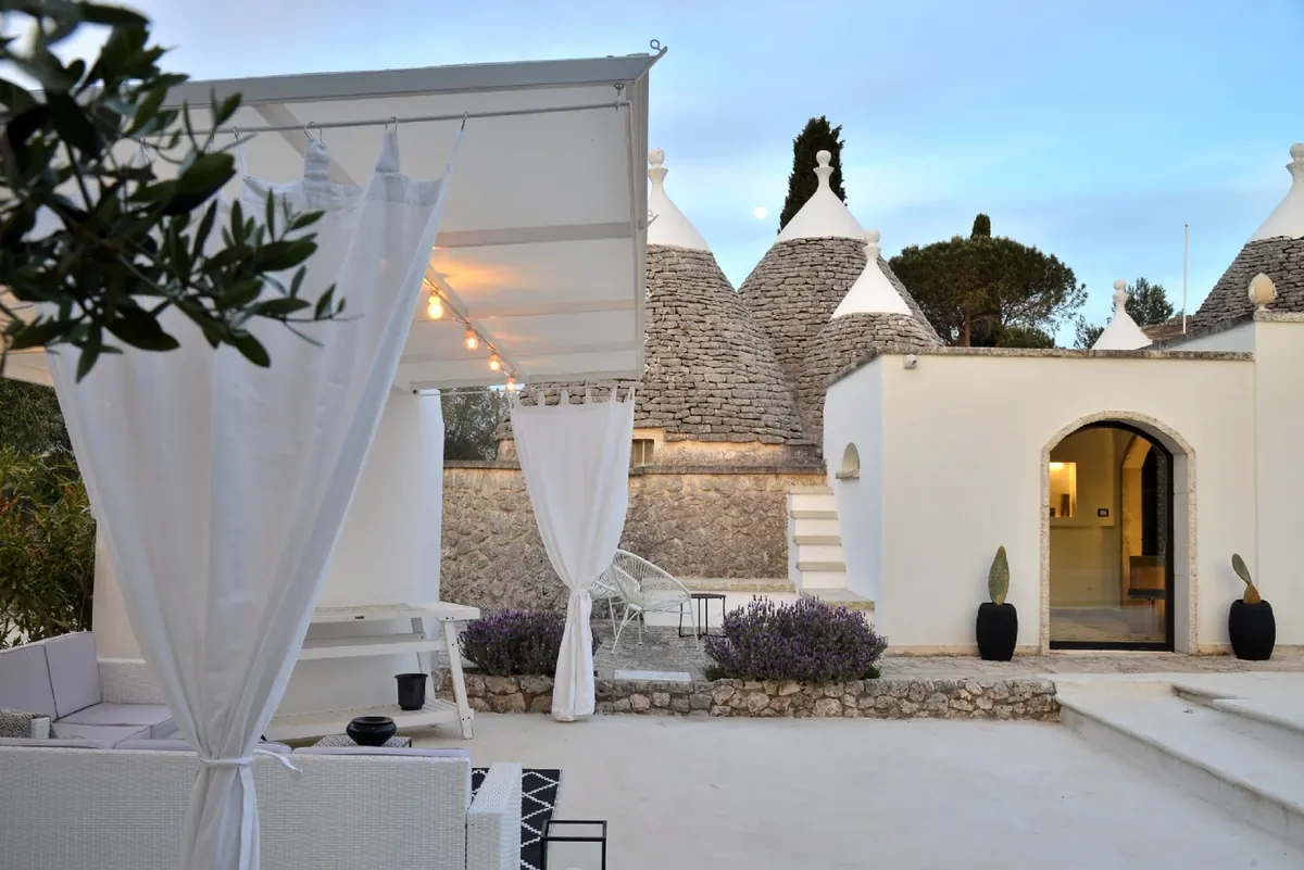 The pergola with white curtains and the trullo cones