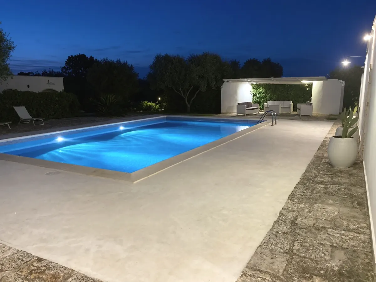 The pool in the evening, lit from under the water, the gazebo glowing