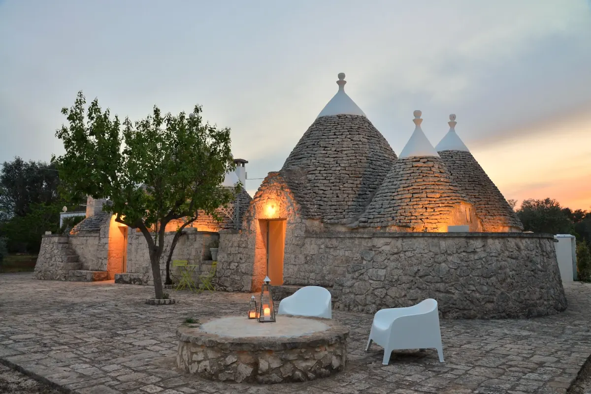 The trulli at dusk, with lanterns on the well