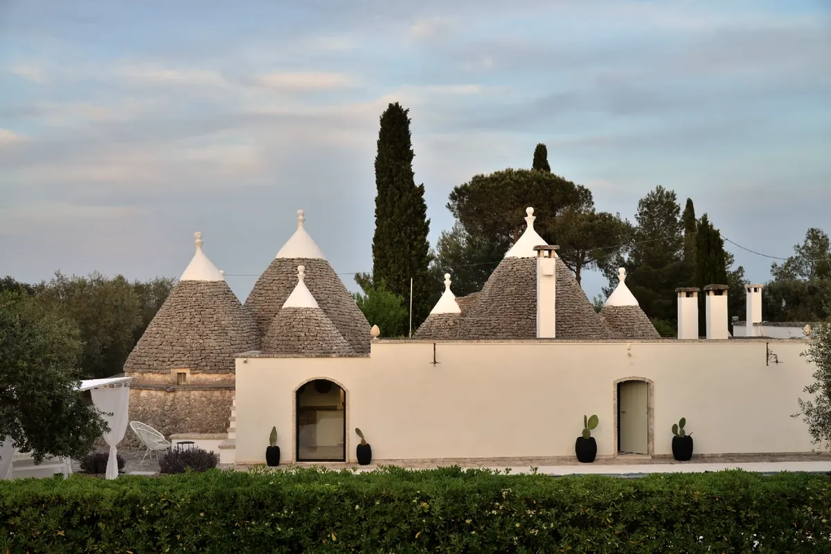 The trullo cones and the white wall at sunset
